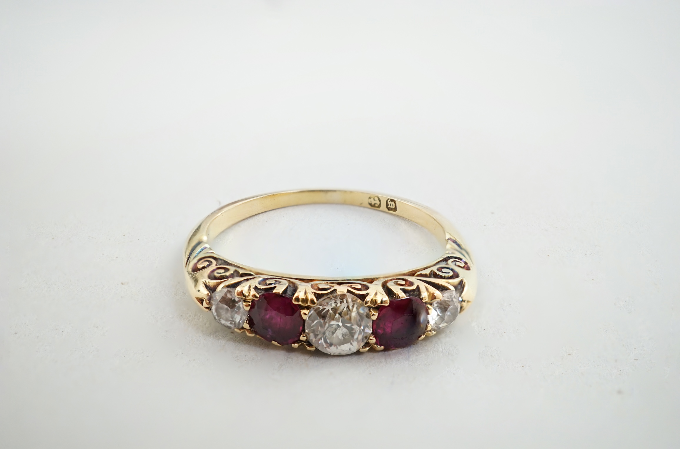 A late Victorian gold, three stone diamond and two stone ruby set half hoop ring